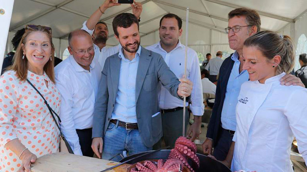 El presidente del Partido Popular, Pablo Casado y el presidente de la Xunta de Galicia, Alberto Núñez Feijóo, acompañados por cargos del partido, hablan con una «pulpeira» en la carpa al final del acto político hoy en la Carballeira de San Xusto, esta mañana en la localidad de Cerdedo-Cotobade. Foto: EFE