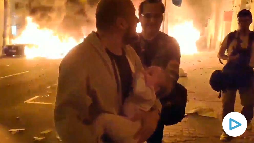 Un padre con su bebé en brazos huye de las llamas.