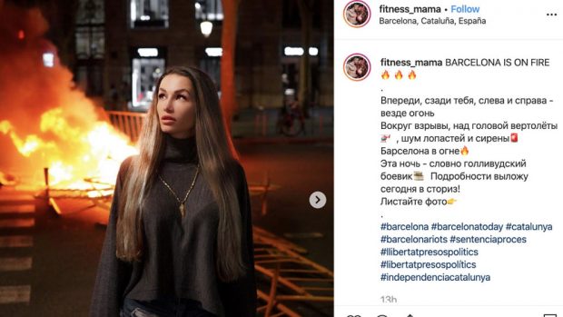 La instagramer rusa @fitness_mama con una barricada ardiendo de Barcelona detrás. 