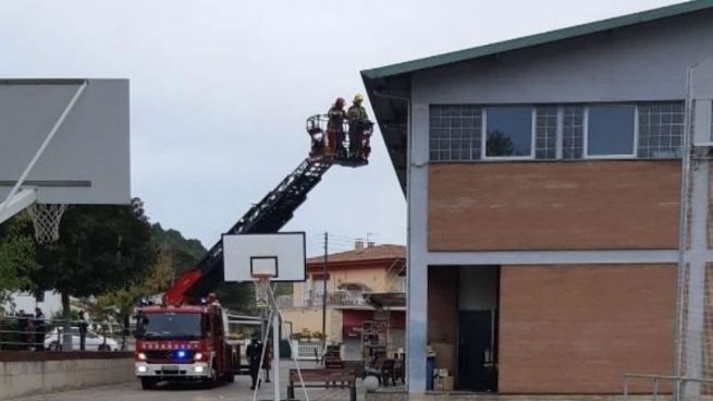 Los bomberos retiran lazos amarillos de la fachada de un colegio en Gerona
