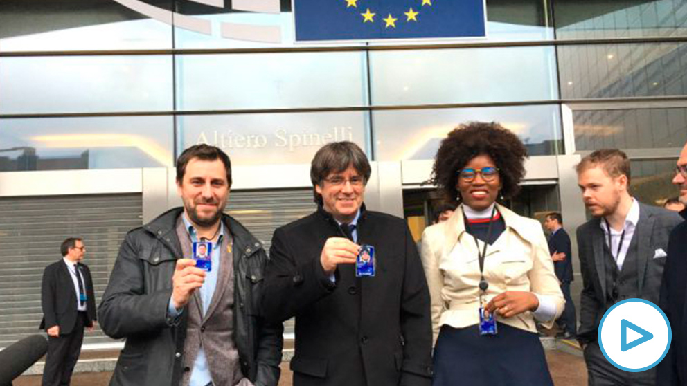 Toni Comín, Carles Puigdemont y la eurodiputada nacionalista flamenca Assita Kanko enseñan sus acreditaciones de eurodiputados.