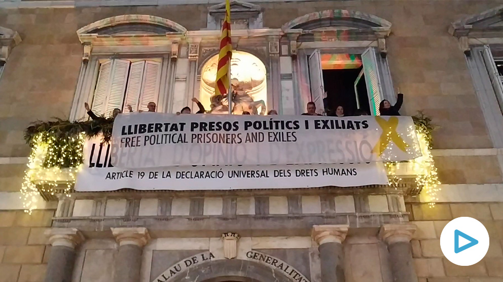 Miembros de la ANC colocan la pancarta de los presos en el balcón de la Generalitat.