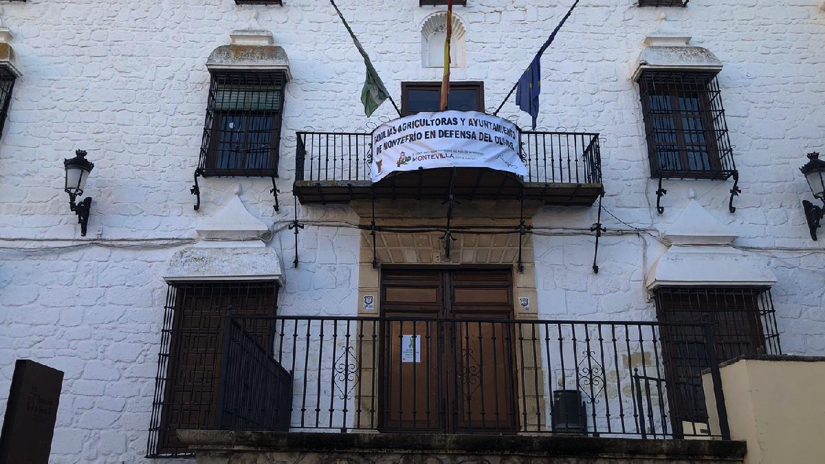 Pancartas en la fachada del ayuntamiento de Montefrío anunciando el cierre de las instalaciones y con las banderas a media asta por el campo español.