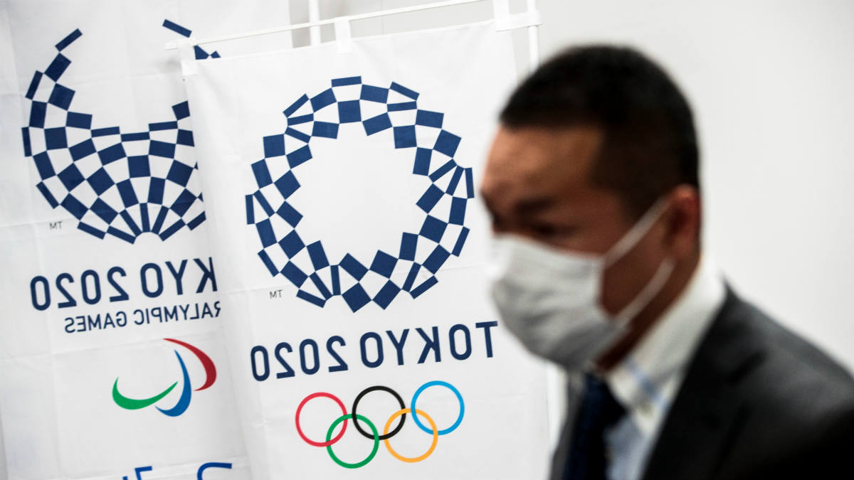 Un reportero con mascarilla ante un stand de los Juegos de Tokio 2020. (AFP)