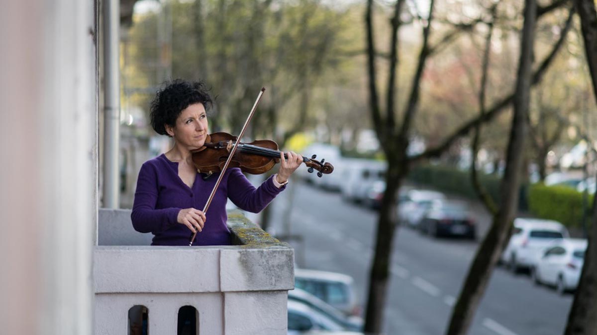 Una vecina de una localidad francesa ameniza el confinamiento a sus vecinos desde su balcón violín en mano. Foto: AFP