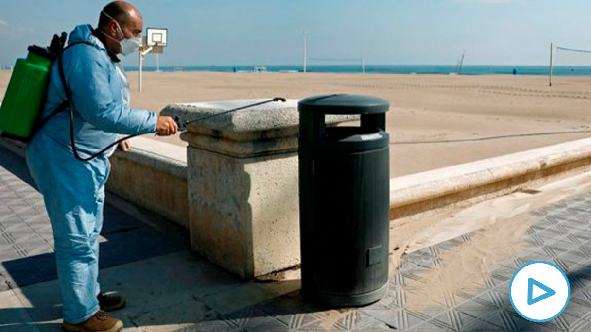 Un operario desinfecta una papelera ante una playa de la Malvarrosa (Valencia) este miércoles. EFE/ Juan Carlos Cárdenas