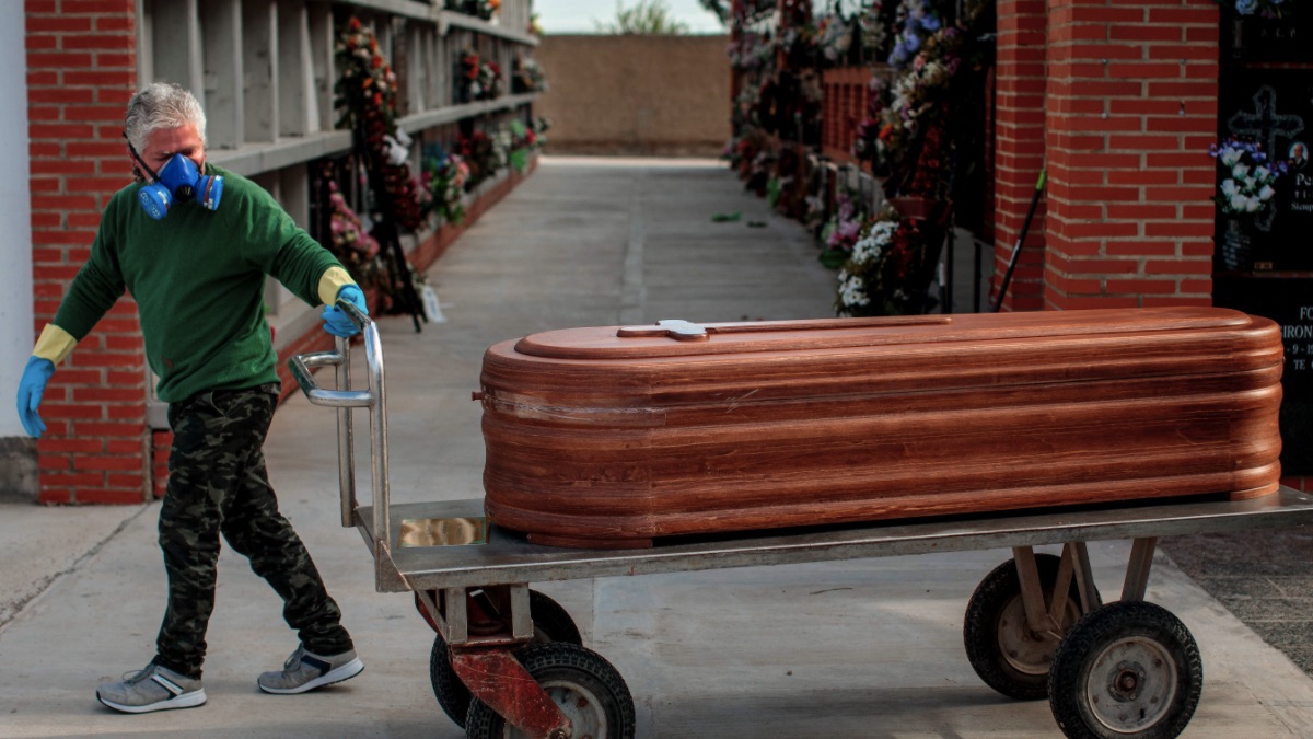 Un operario de un cementerio de València traslada un féretro seguido por los familiares de la víctima durante un entierro. (Foto: EFE:Biel Aliño)
