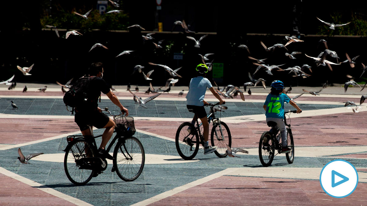 Dos niños y un adulto pasean en bicicleta por la Plaza de Cataluña de Barcelona este martes, cuando se cumplen 45 días de confinamiento por el estado de alarma decretado por el Gobierno por la crisis del coronavirus. EFE/Enric Fontcuberta