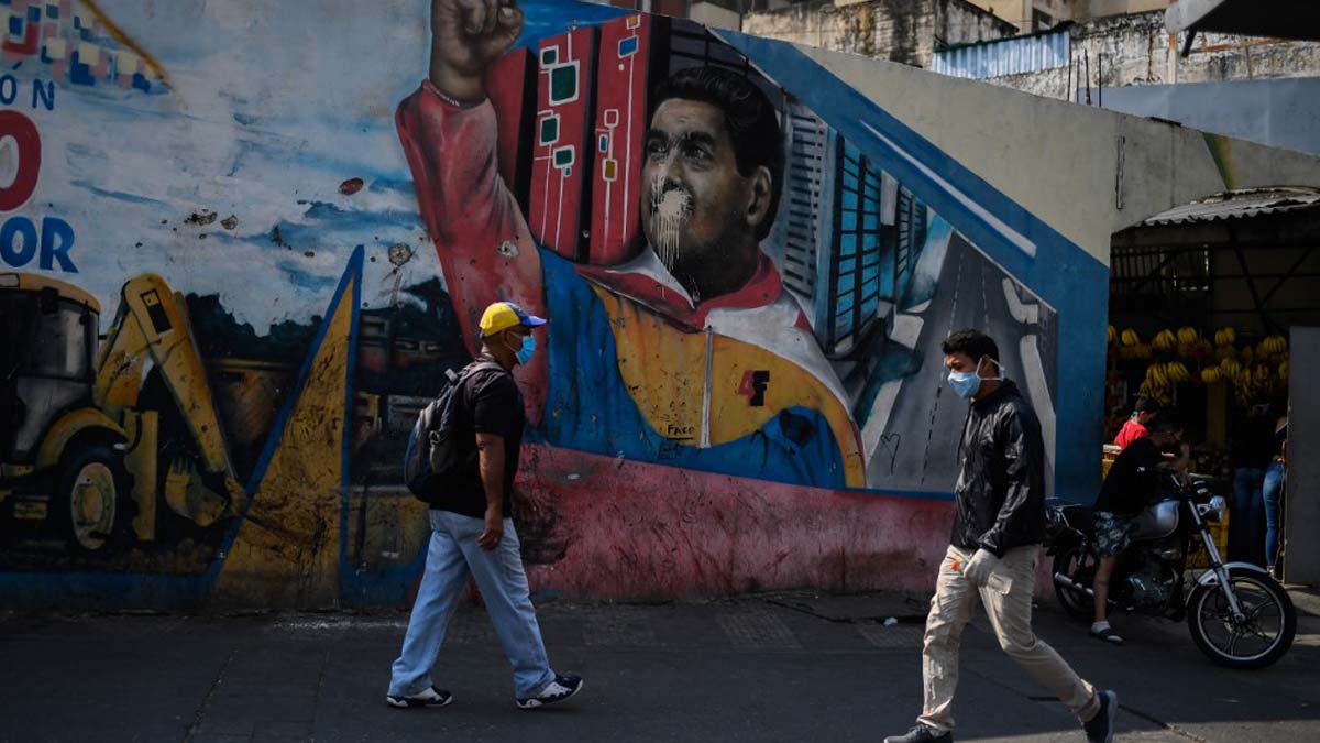 Dos venezolanos llevando mascarillas para protegerse contra el coronavirus por una calle de Caracas, la capital de Venezuela. Foto: AFP