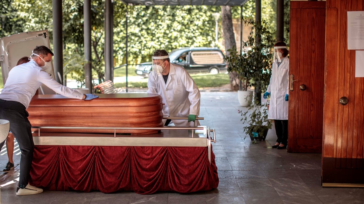 Operarios de una funeraria de Valencia manejan el féretro de una víctima del COVID-19.