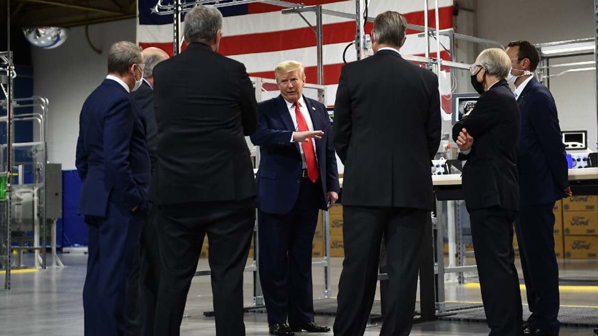 Donald Trump, sin mascarilla, rodeado de gente con mascarillas durante su visita a la fábrica norteamericana de Ford. Foto: AFP