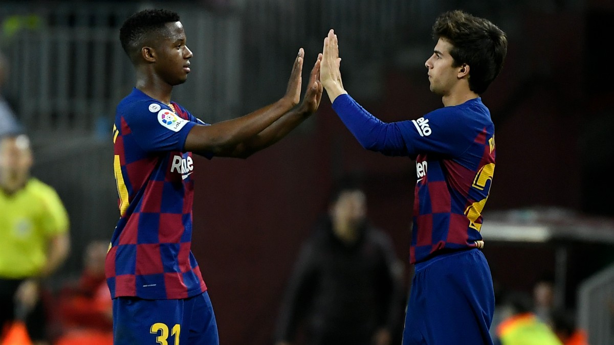 Riqui Puig y Ansu Fati chocan las manos durante un partido. (AFP)