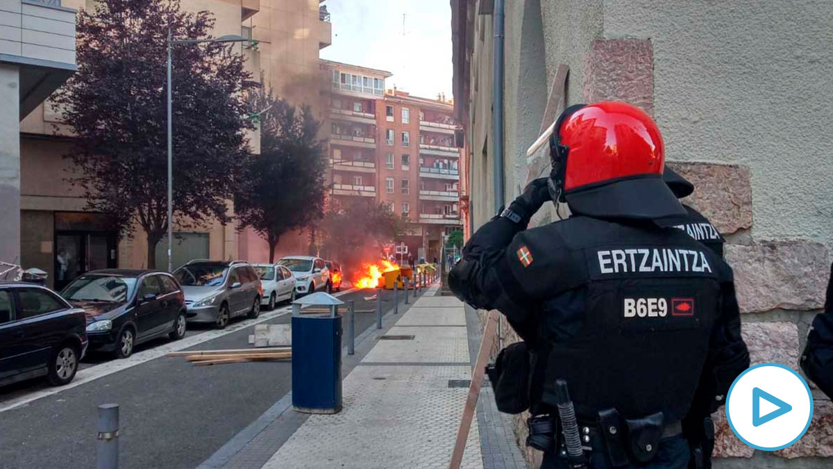 Un ertzaintza observa la quema de contenederos. Foto: Europa Press