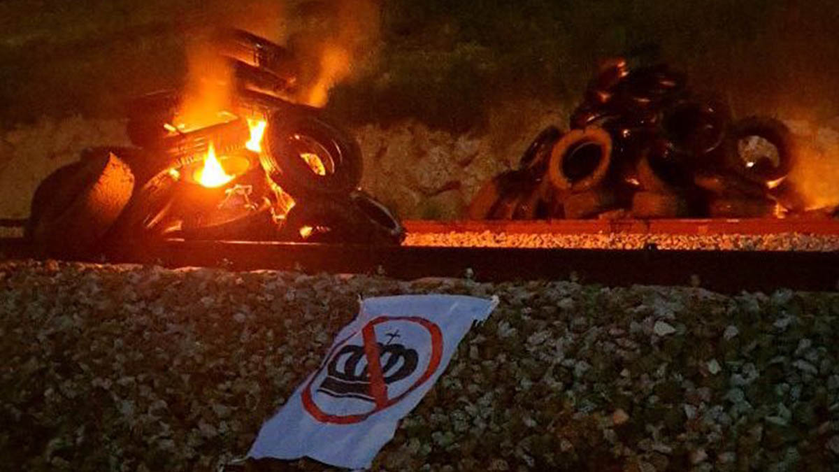 Neumáticos ardiendo sobre las vías del AVE junto a un pancarta antimonárquica. (Twitter)