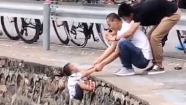 Un padre sujeta a su hijo al borde de un precipicio por una foto en China
