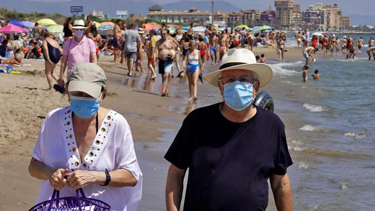 Dos personas pasean, este domingo, por la orilla de la playa de La Patacona de Alboraia protegidos con mascarillas.