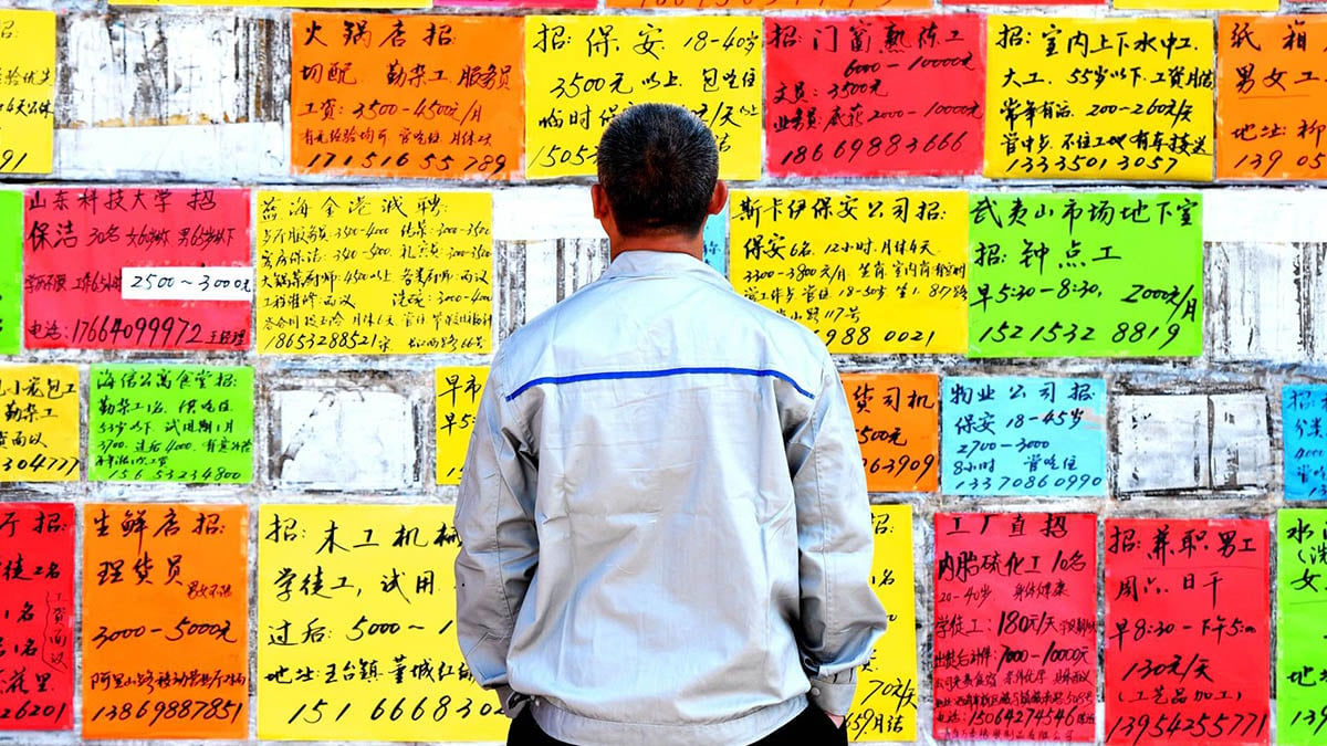 Un transeunte contempla anuncios de trabajo en un mural de la ciudad china de Quingdao.