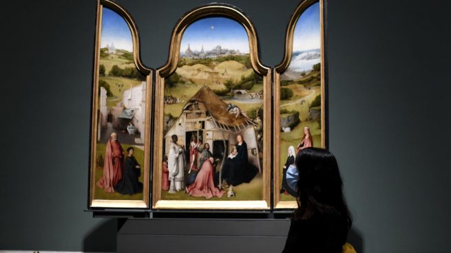 Una persona posa por delante de la obra 'Adoración de los Magos' del Bosco el día de la reapertura de la sala donde permanecen las obras del artista, ubicadas en el Museo del Prado, en Madrid