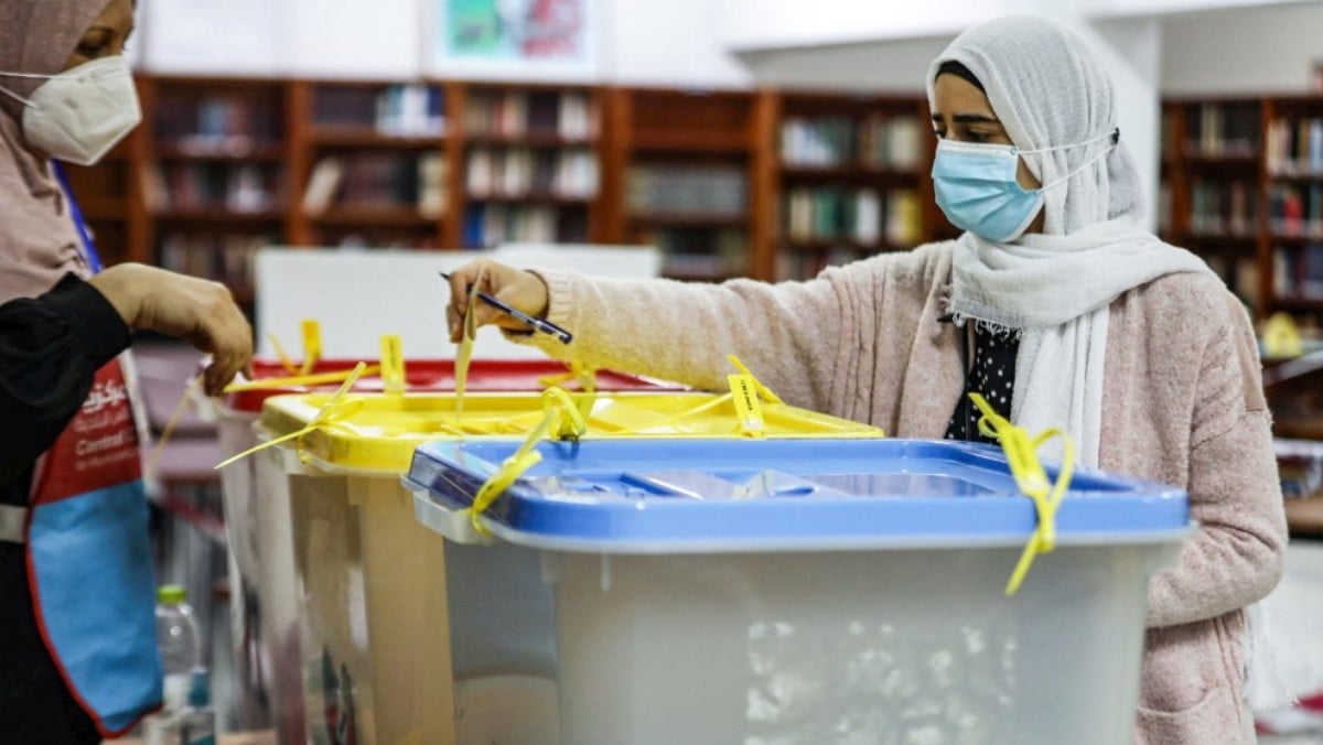 Una mujer libia deposita su voto ataviada con mascarilla y velo. Foto: AFP