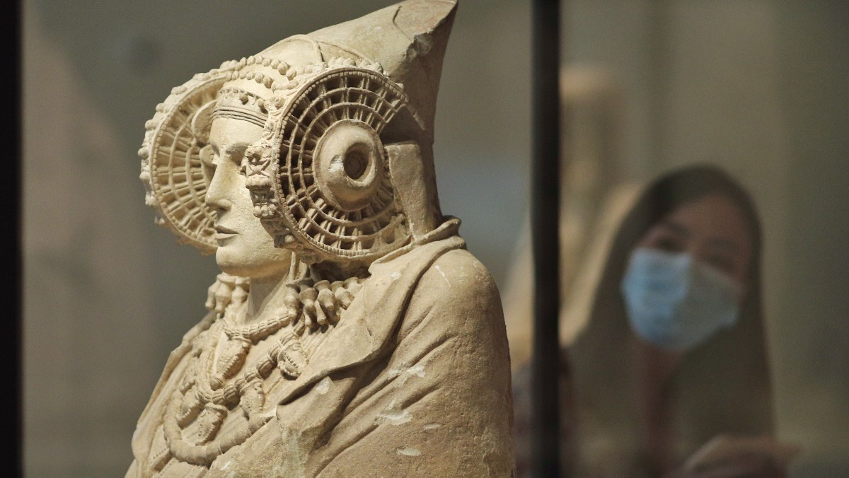 Una persona protegida con mascarilla observa la escultura de La Dama de Elche disponible en el Museo Arqueológico de Madrid. Foto: EP