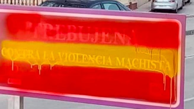 Tapan con una bandera de España un cartel contra la violencia de género en Cádiz