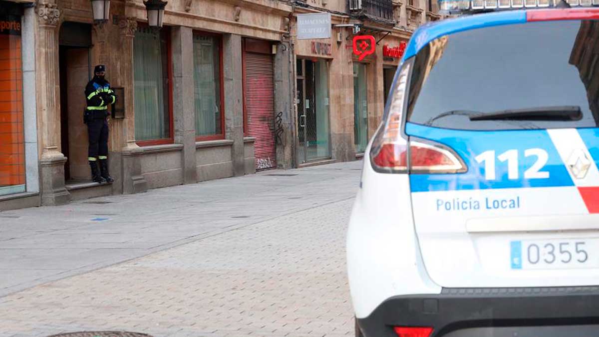 Un agente de la Policía Local de Salamanca vigila a las puertas de un local durante las labores de investigación de una «fiesta clandestina». Foto: EFE