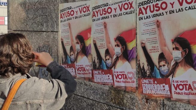 Una simpatizante del Sindicato de Estudiantes colocando un cartel a favor de Pablo Iglesias y Unidas Podemos.