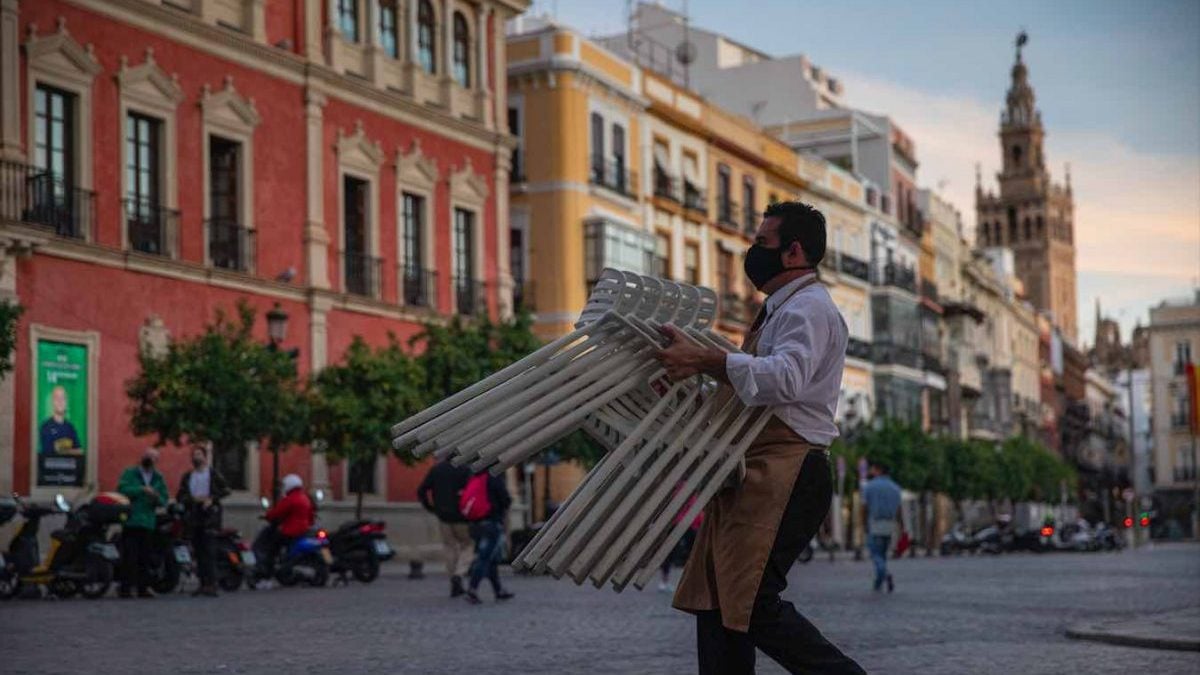 Un hostelero recoge el mobiliario de la terraza de un bar de Sevilla (María José López / Europa Press).