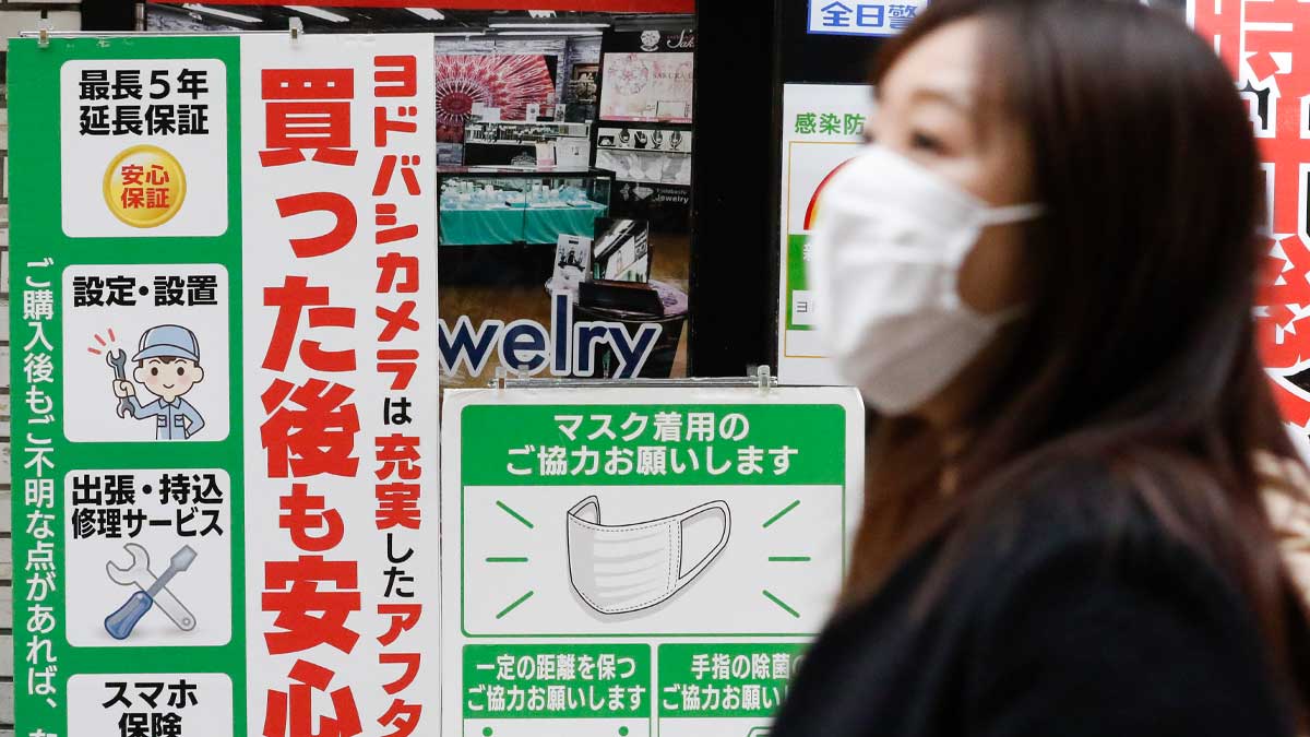 Una joven japonesa con mascarilla frente a carteles informativos sobre el Covid. Foto: EP