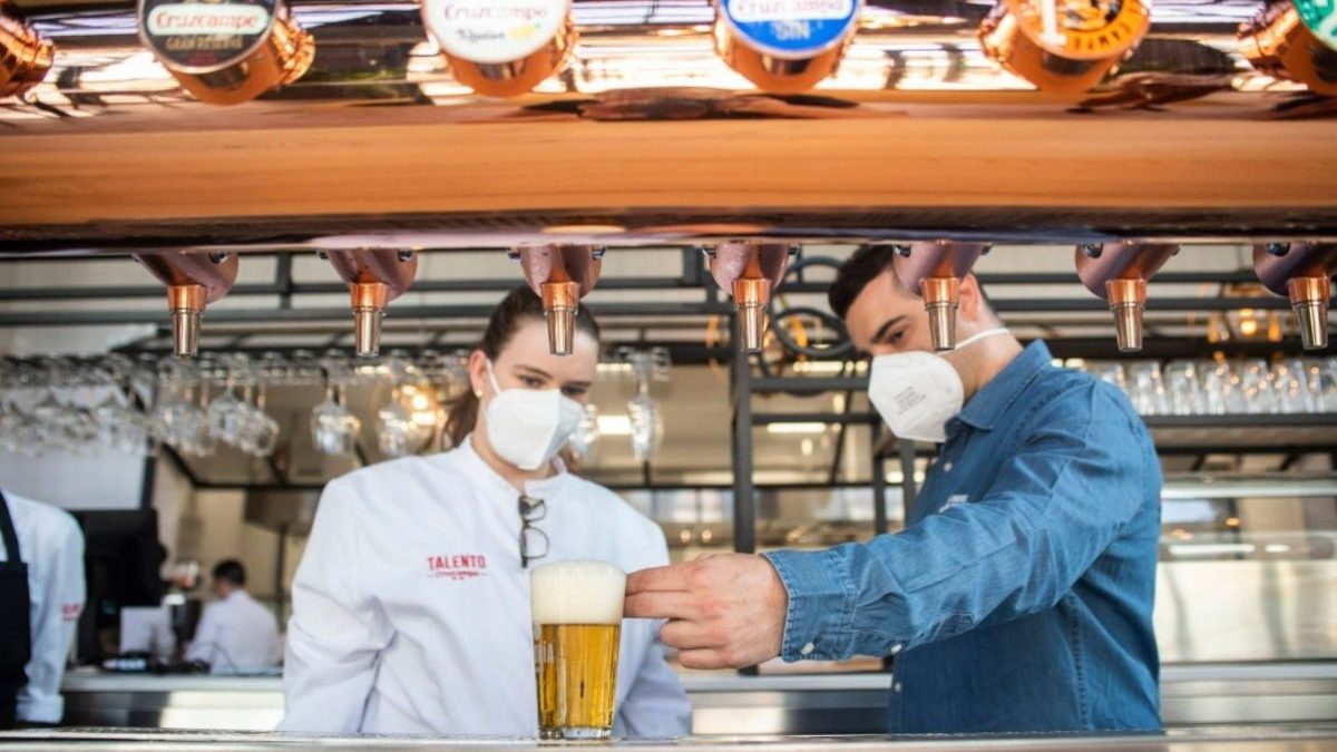 Dos camareros sirviendo una cerveza en su establecimiento (CRUZCAMPO).