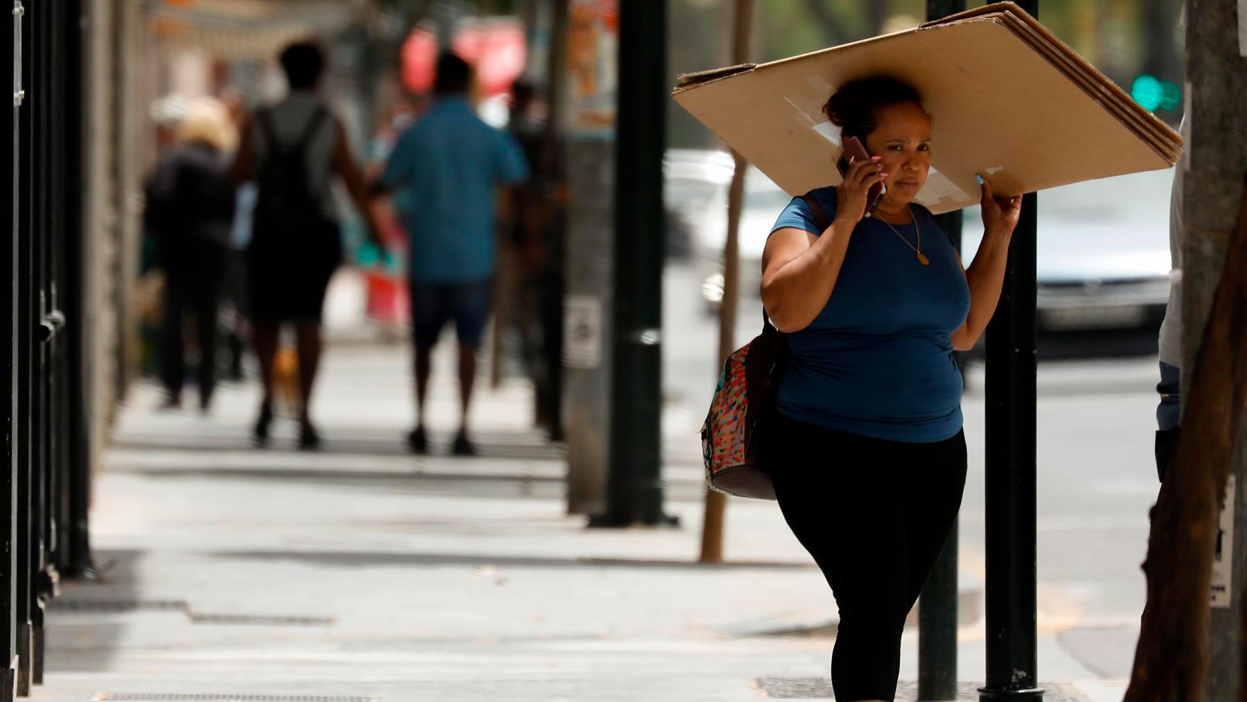 Una mujer se resguarda del sol con un cartón. Foto: EP