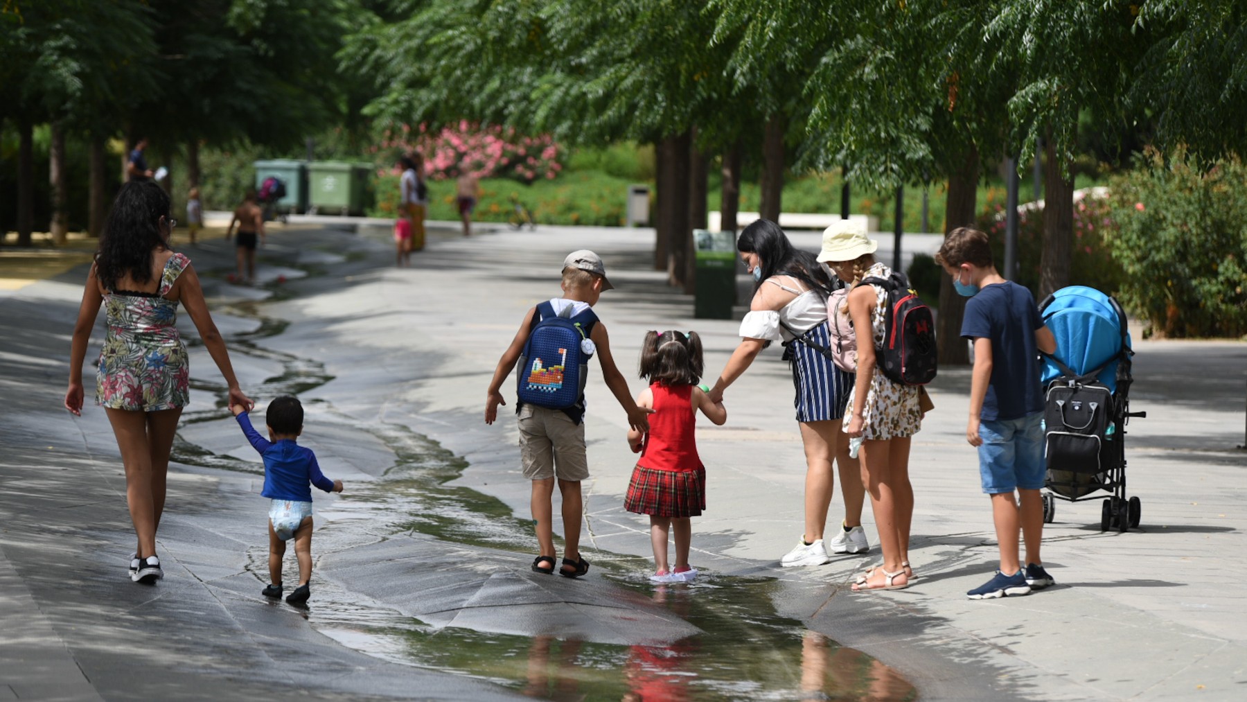 Varios niños pasan por un arroyo de agua en Valencia.