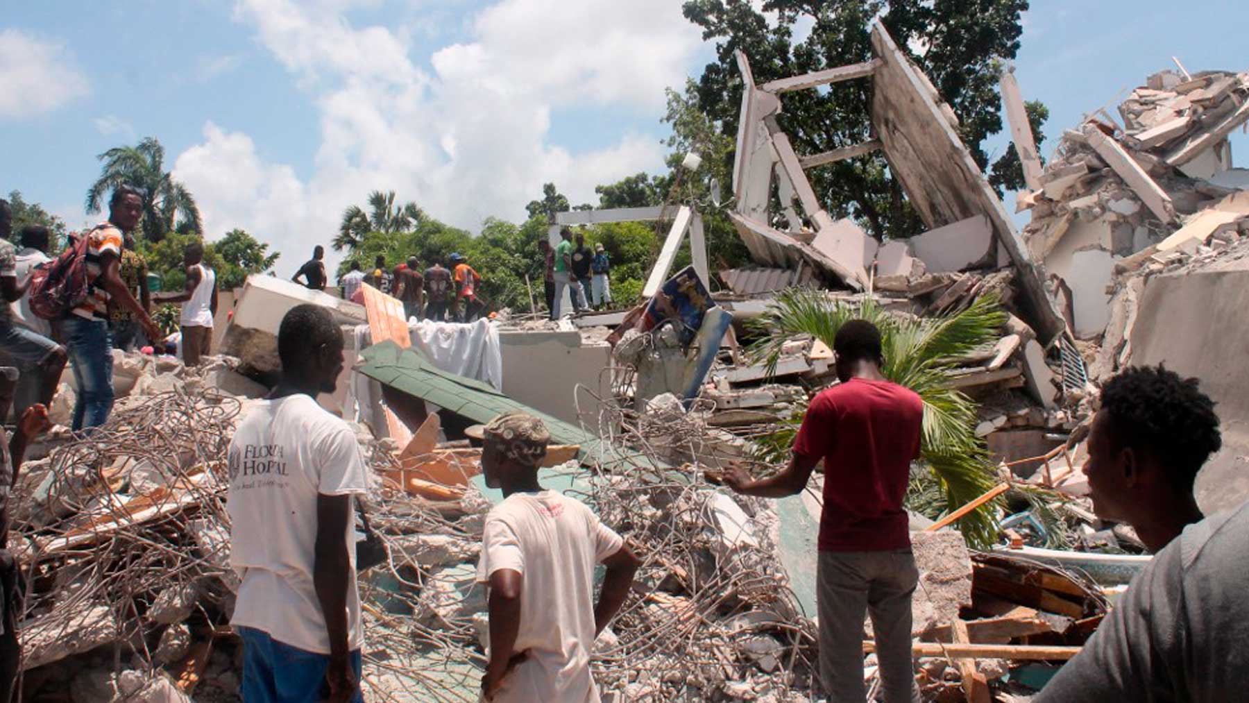 Varias personas observan una casa derrumbada en Puerto Príncipe, tras el terremoto que asoló Haití. Foto: AFP