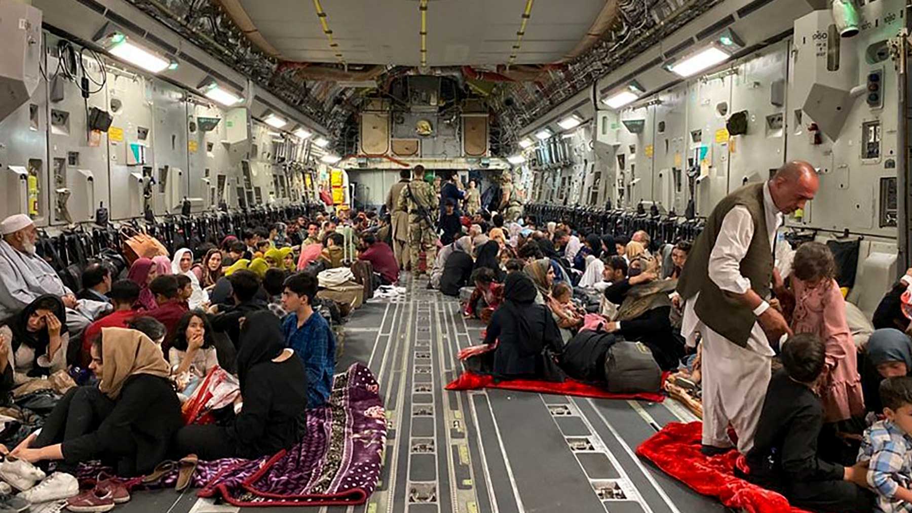 Varias familias afganas en el interior de un avión militar de Estados Unidos saliendo de Afganistán. Foto: AFP
