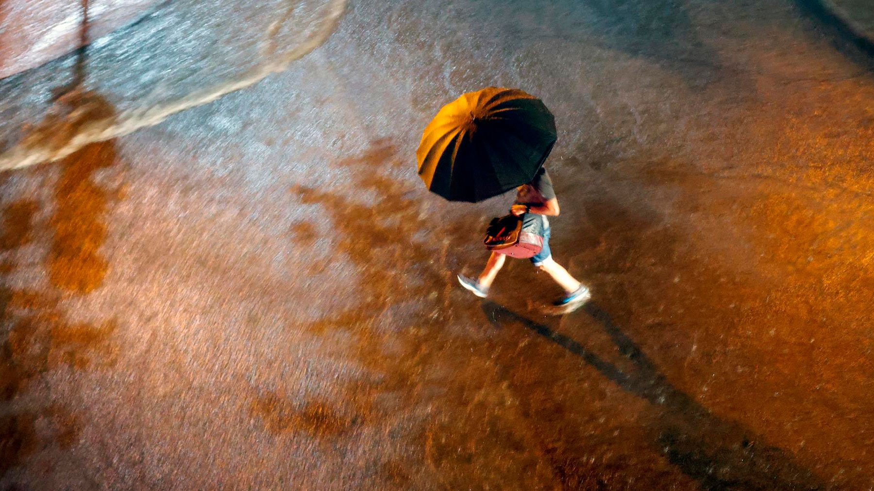 Una persona cruza una calle bajo la lluvia durante la noche del primer día de septiembre que ha traído fuertes lluvias a España. Foto: EFE