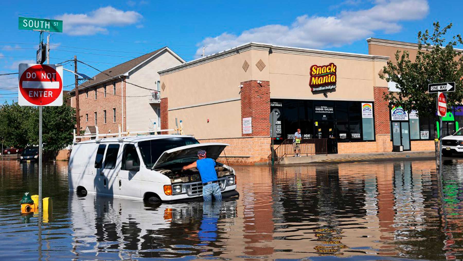 Un hombre trata de reparar su coche en Newark, estado de Nueva Jersey, tras el paso del huracán ‘Ida’. Foto: AFP