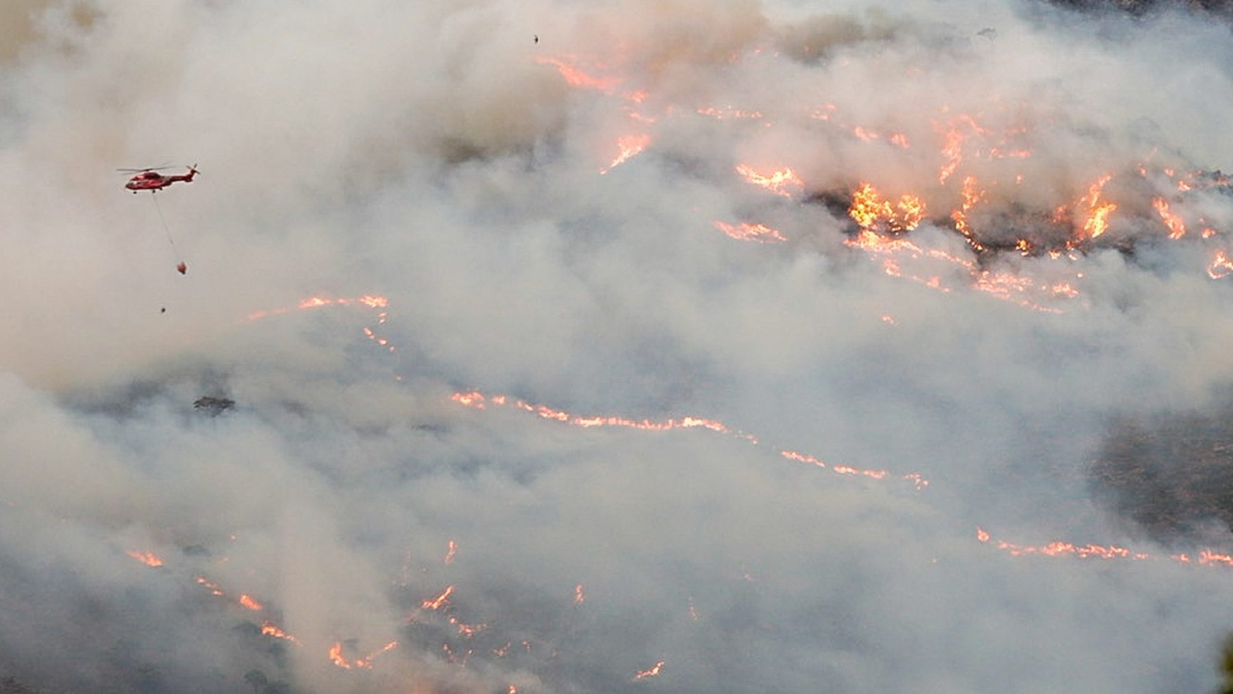 Un helicóptero sobrevuela el fuego desatado en Sierra Bermeja (ÁLEX ZEA / EUROPA PRESS). (1)