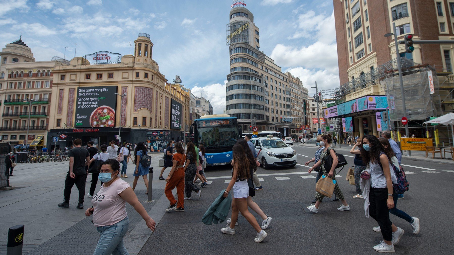 Varias personas caminan por la Gran Vía con mascarilla.