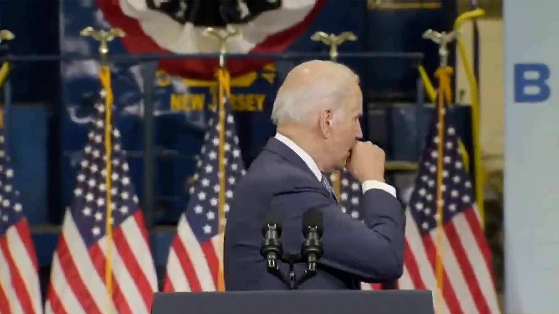 Joe Biden tose en su mano durante un evento y saluda con esa misma mano a los invitados.