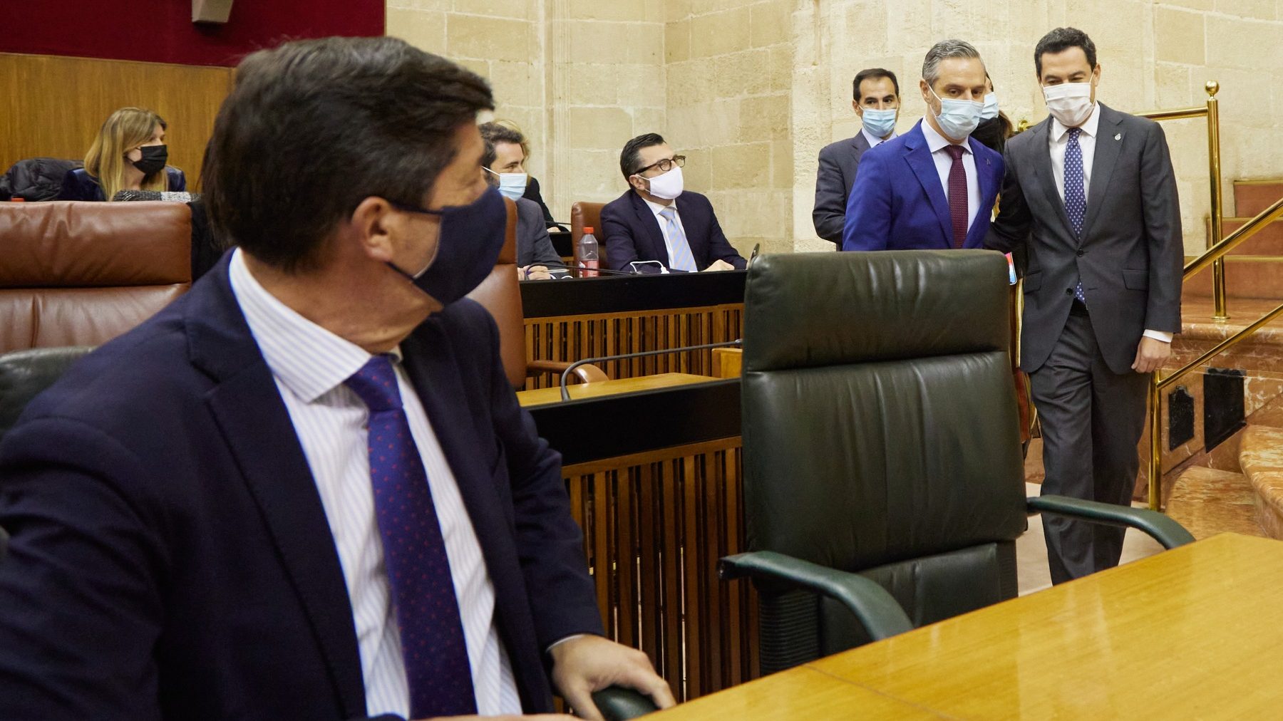 Marín (i) espera sentado a Juan Bravo y Juanma Moreno en el Parlamento de Andalucía (JOAQUÍN CORCHERO / EUROPA PRESS).