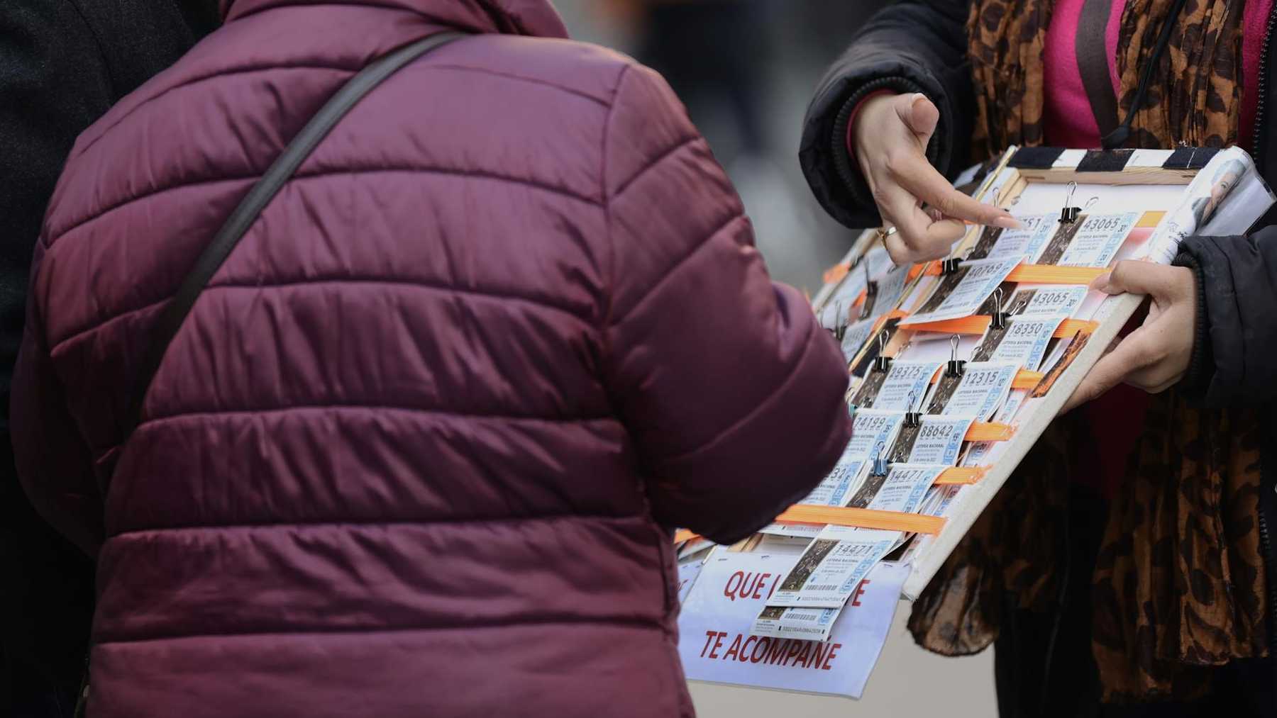 Una mujer compra un décimo de lotería a una vendedora ambulante. – Eduardo Parra – Europa Press.