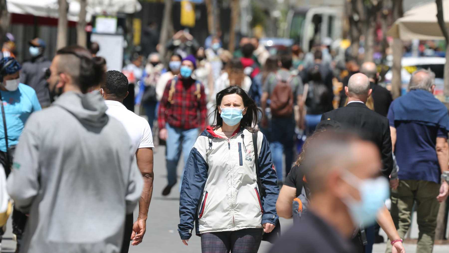 Varios ciudadanos caminan por la calle con mascarilla.