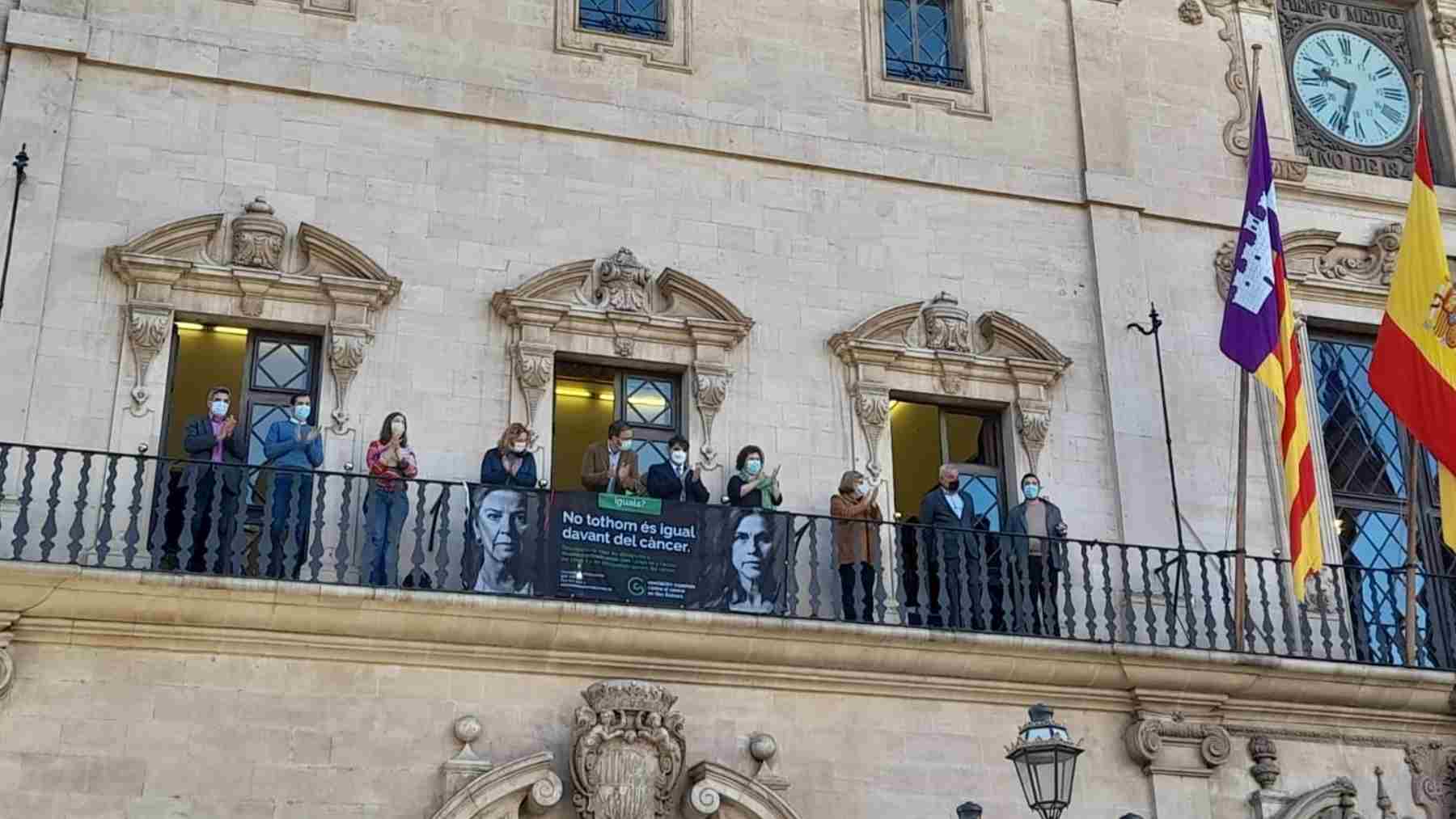 José Hila y el presidente de la AECC en Baleares, José Reyes, cuelgan una pancarta en la fachada de Cort.