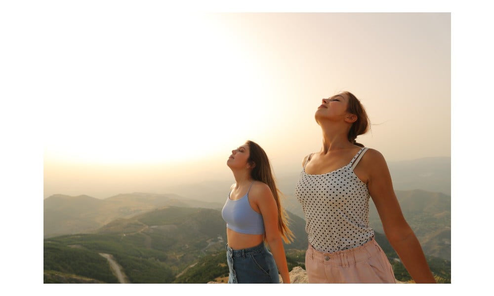 Dos chicas en medio de la montaña respirando profundamente