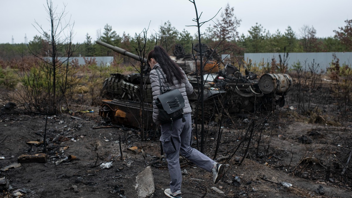 Una mujer pasa junto a un tanque ruso quemado.