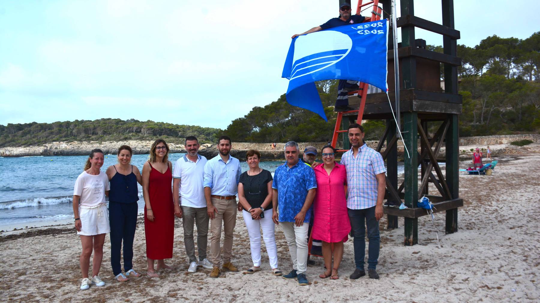 Las autoridades municipales junto a la bandera azul en la playa de Cala Mondragó.