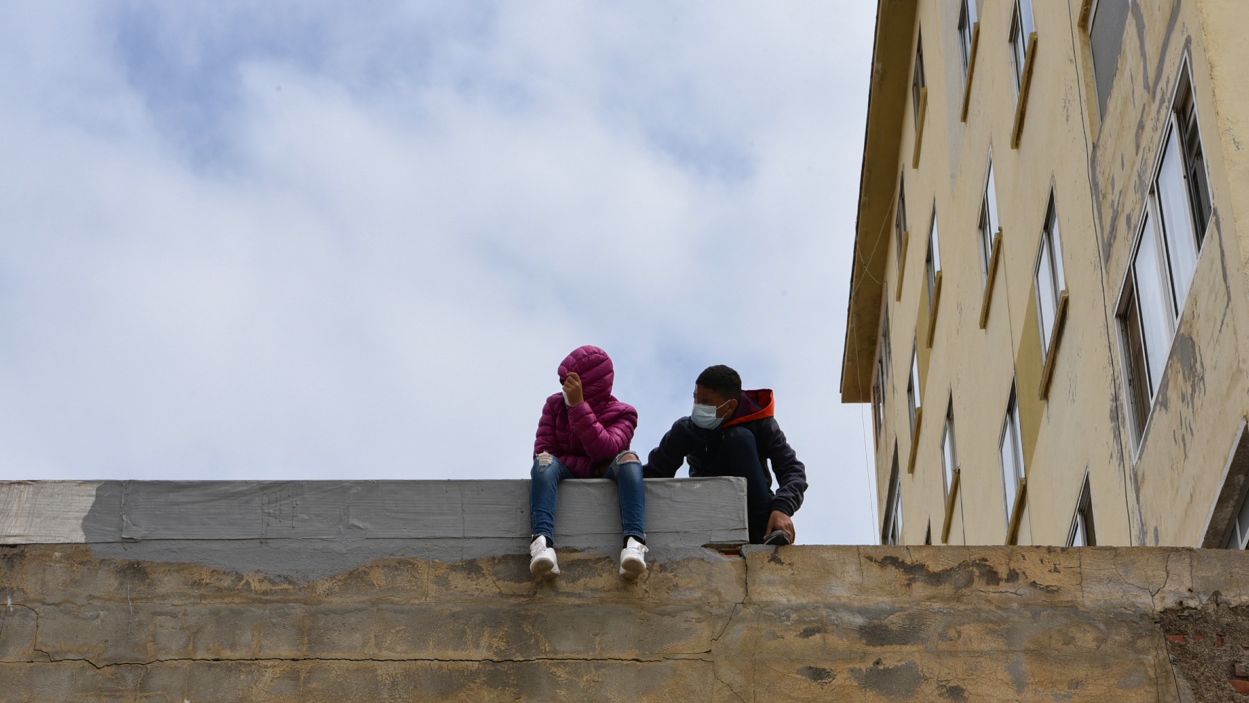 Dos menores marroquíes sentados sobre un muro en una nave de Ceuta (EUROPA PRESS).