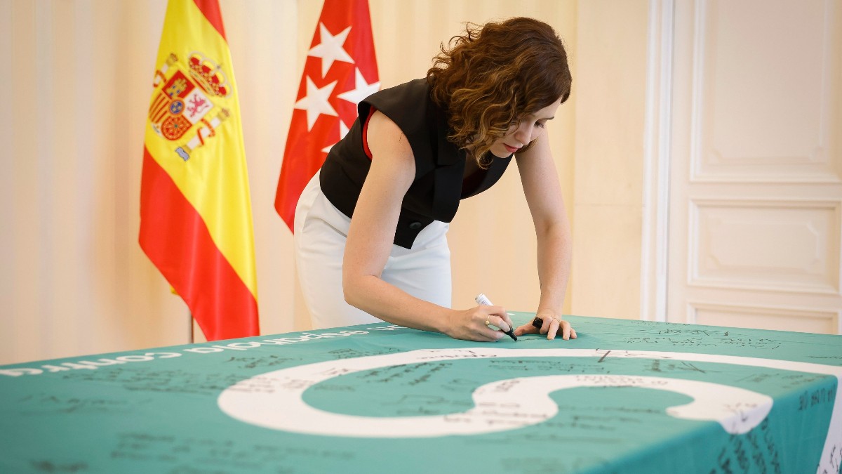 La presidenta de la Comunidad de Madrid, Isabel Díaz Ayuso, firma la bandera de la AECC. Archivo.