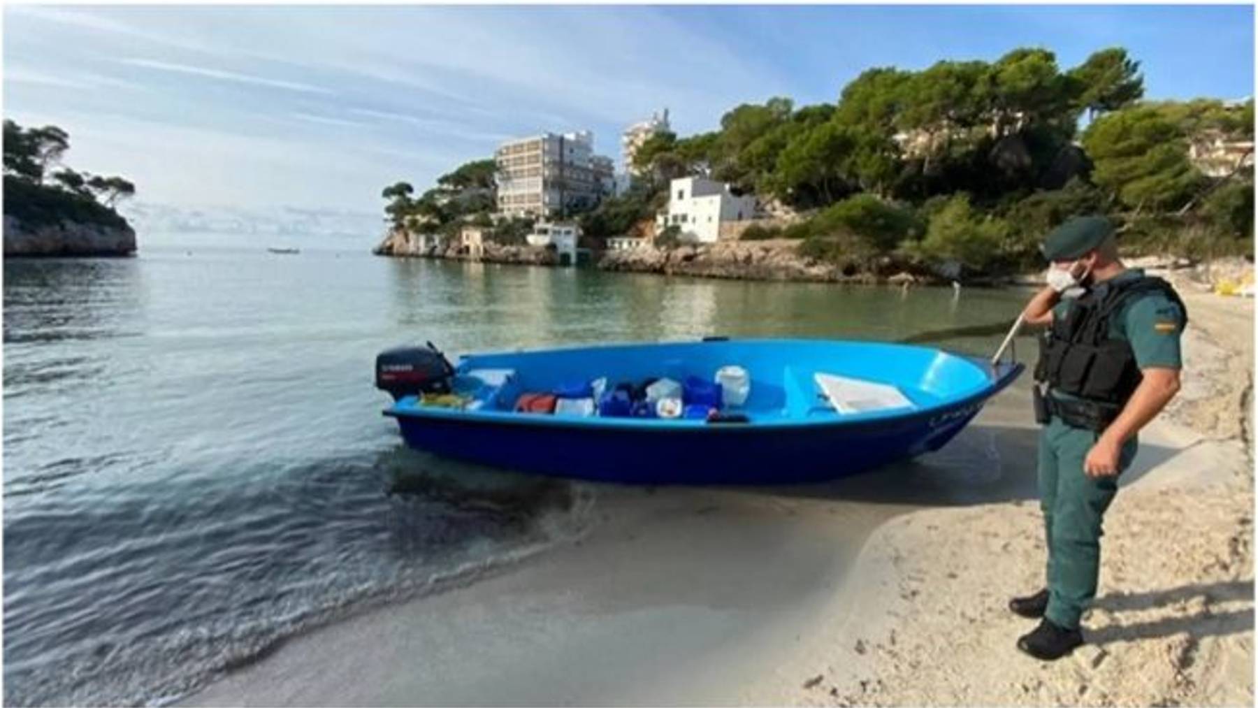 Un agente de la Guardia Civil junto a una patera en la costa de Mallorca.