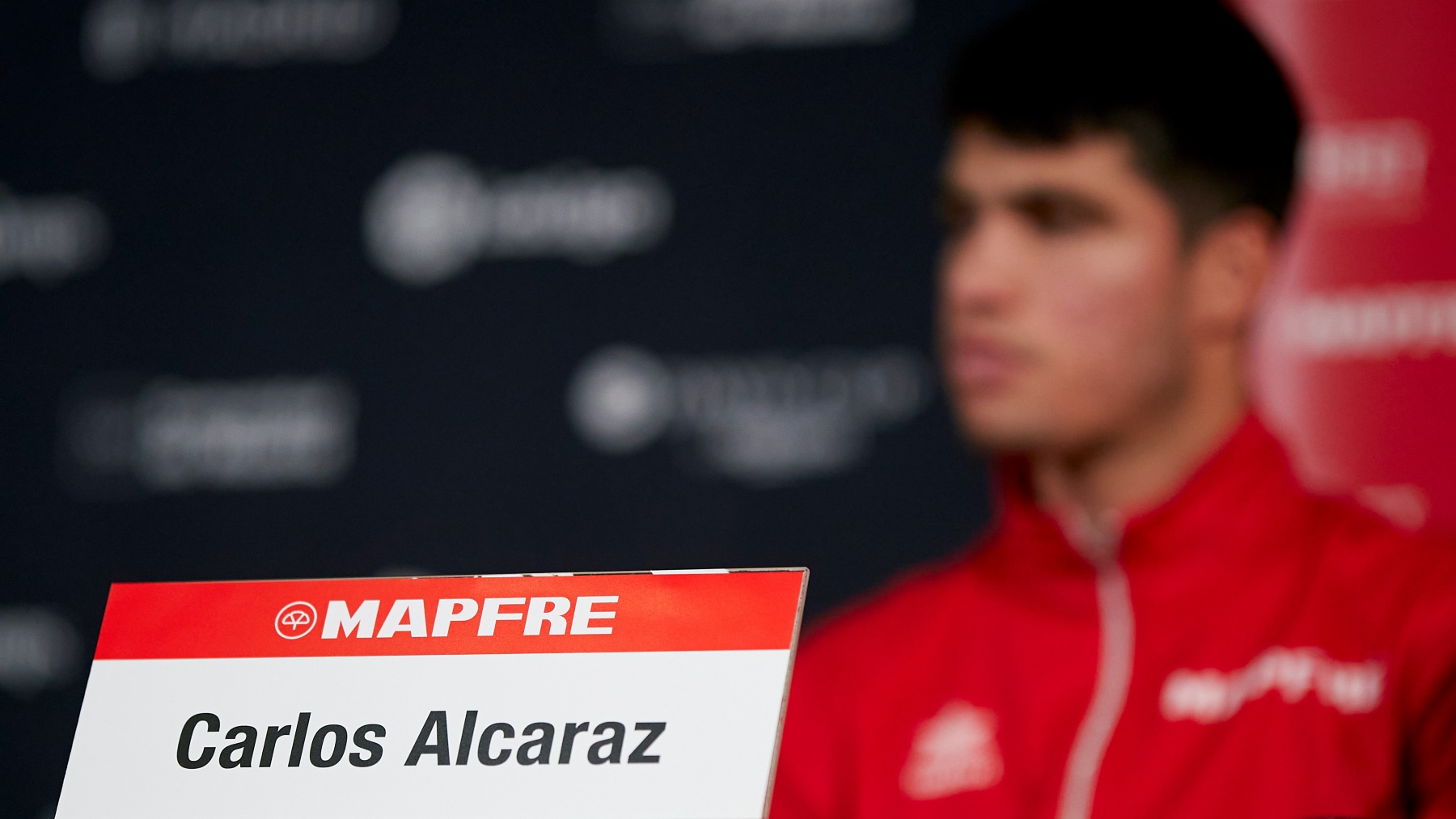 Carlos Alcaraz, de fondo, en una rueda de prensa. (Kosmos Tennis)